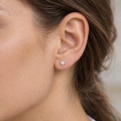 Illustration of a small round cubic zirconia stud in a sterling silver setting, worn on an ear