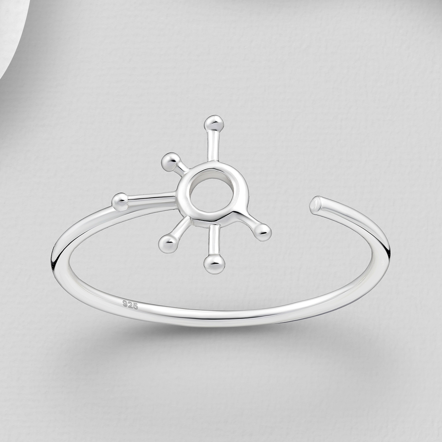 Atomic adjustable sterling silver ring with an open sunburst design against a grey background