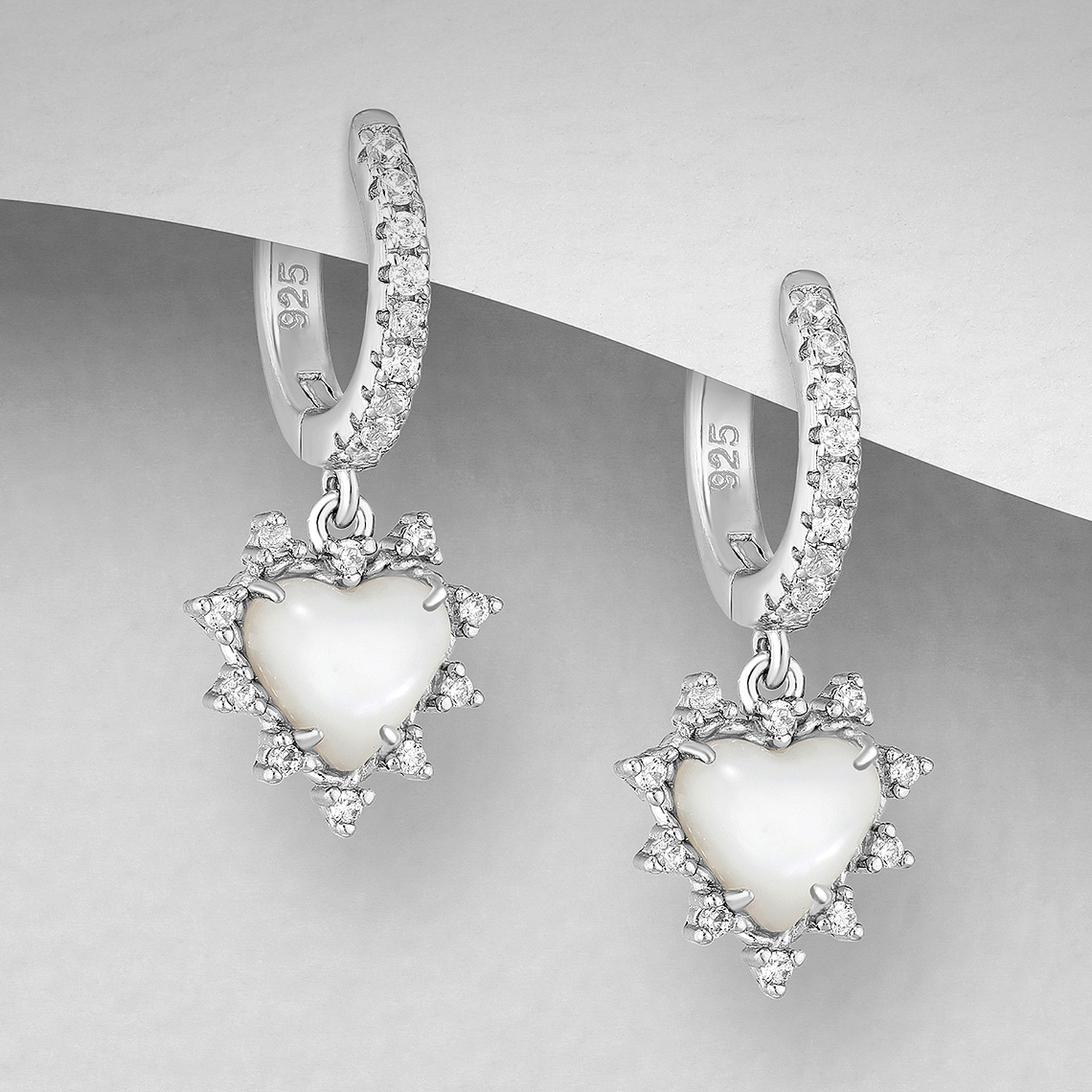 Sterling silver cubic zirconia hoops with spiky heart drops, on a grey display card
