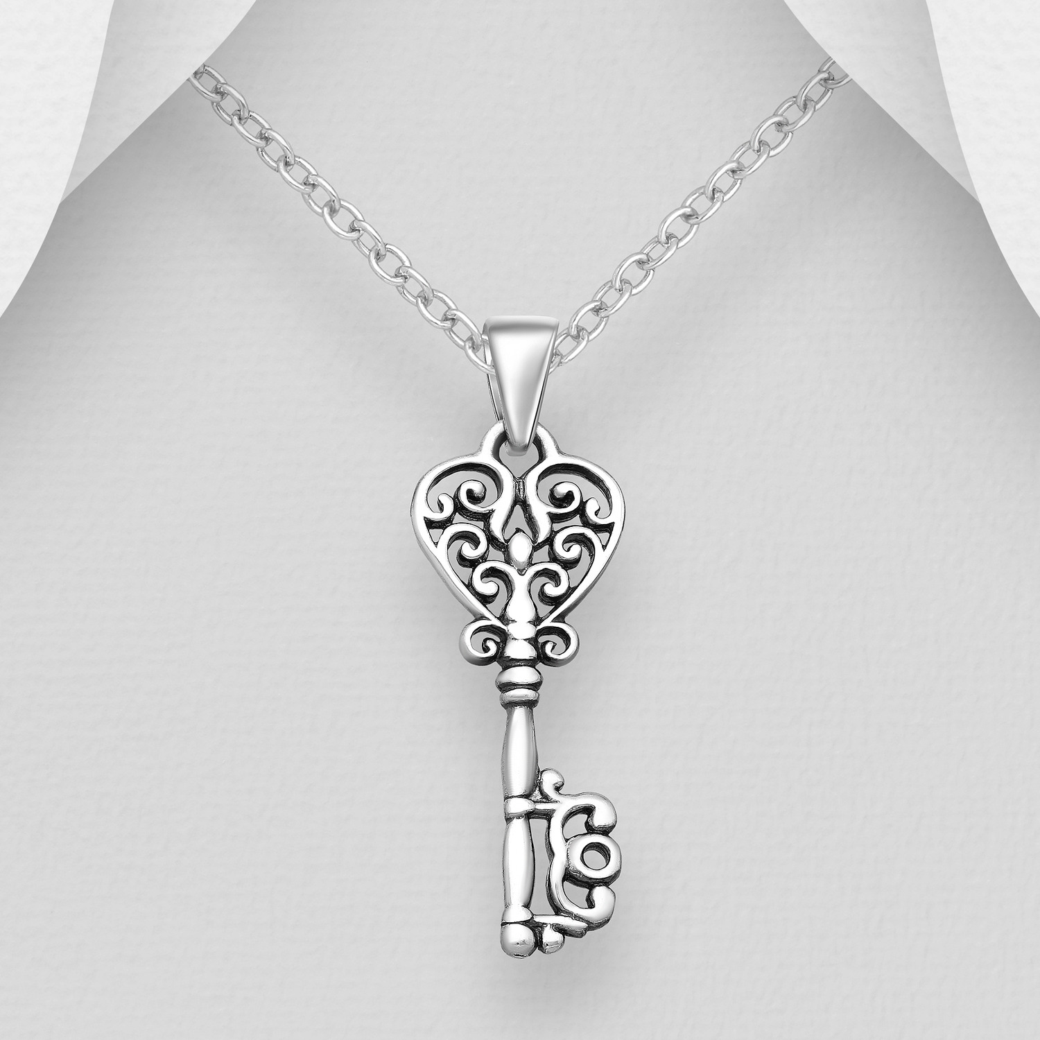 Sterling silver oxidised key pendant shown on a chain against a grey background