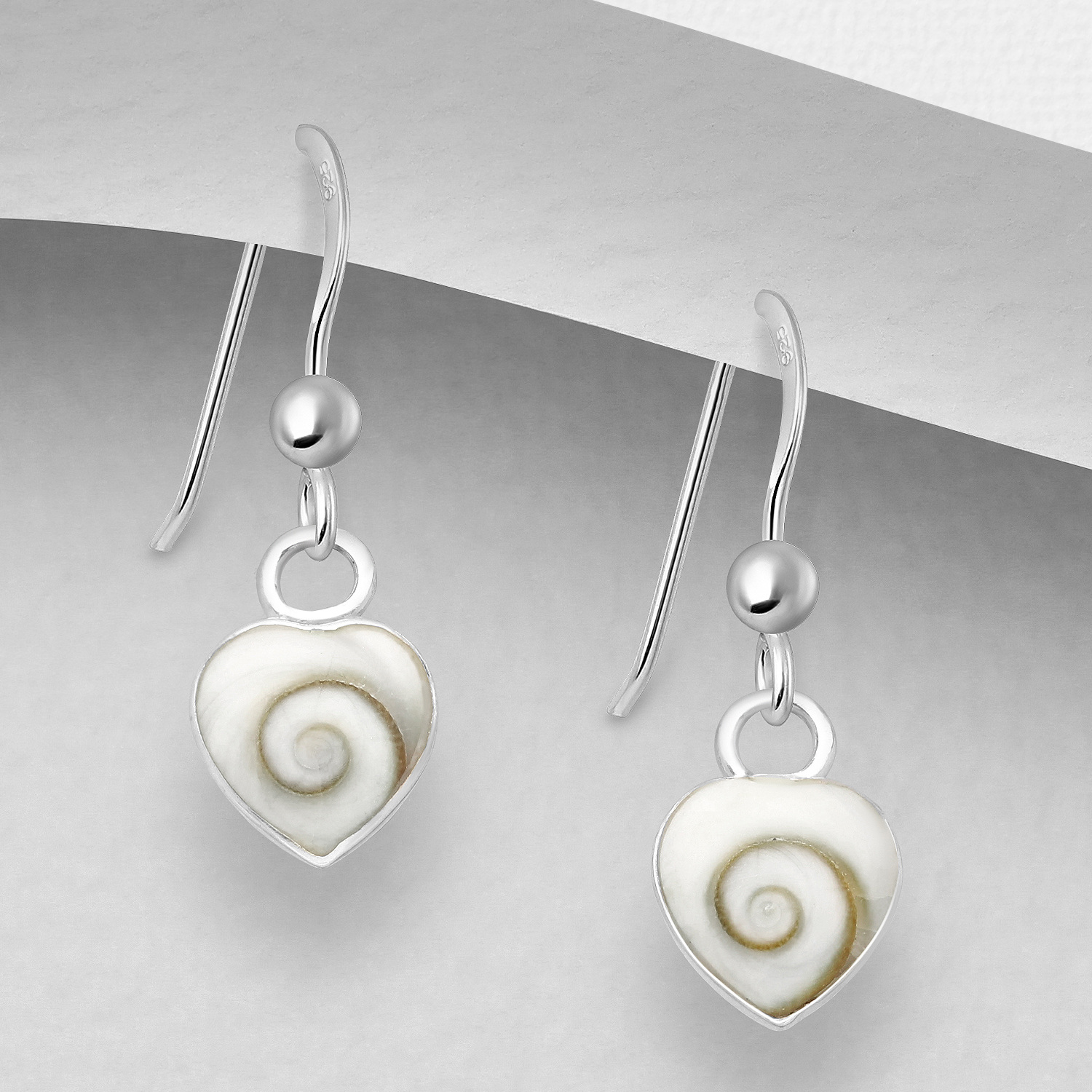 Sterling silver shiva shell heart earrings, on a grey display card
